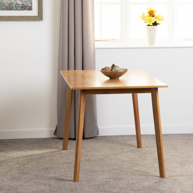 Wooden dining table in a room with a window and curtains.