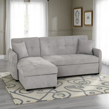Gray sectional sofa in a living room with a patterned rug and framed pictures on the wall.