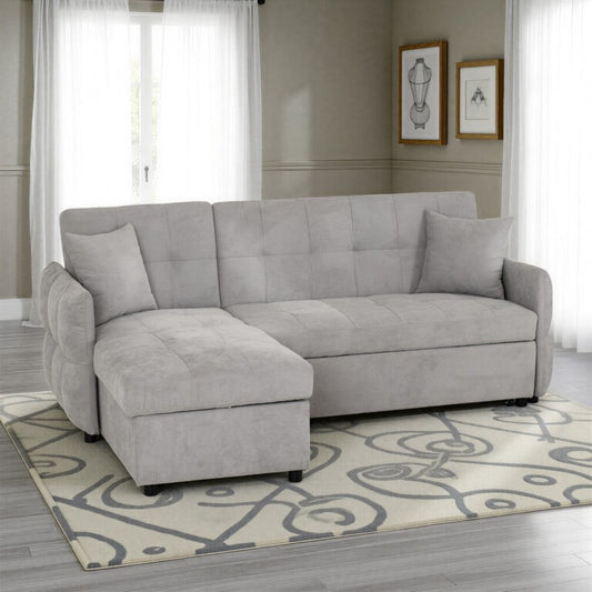 Gray sectional sofa in a living room with a patterned rug and framed pictures on the wall.