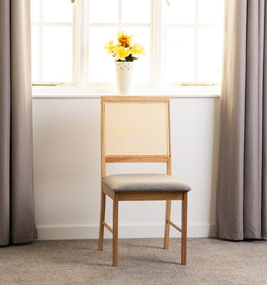 Ellis wooden chair with wicker backrest and cushioned seat in a room with curtains and a window.