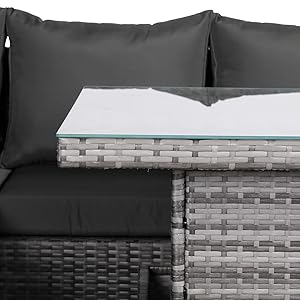 Gray wicker outdoor furniture set with glass top table and black cushions.