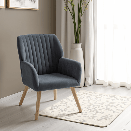 Gray upholstered chair with wooden legs in a room with a rug and plant.