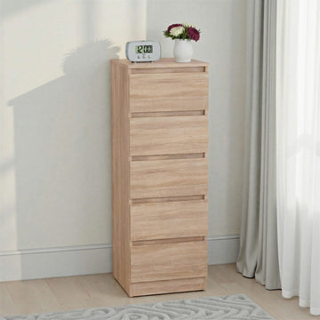 Malvern 5 Drawer Narrow Chest – Sonoma Oak Effect with drawers against a white wall, featuring a digital clock and small plant on top.