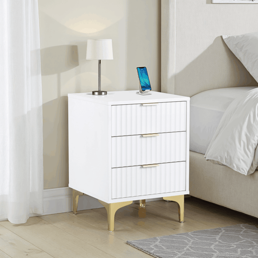 White nightstand with gold legs next to a bed in a bedroom setting
