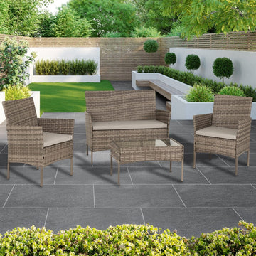 Garden furniture set with chairs and a table on a patio area with greenery.