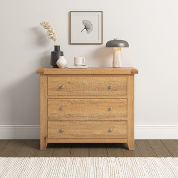 Wooden dresser with three drawers in a room setting with decor items on top.