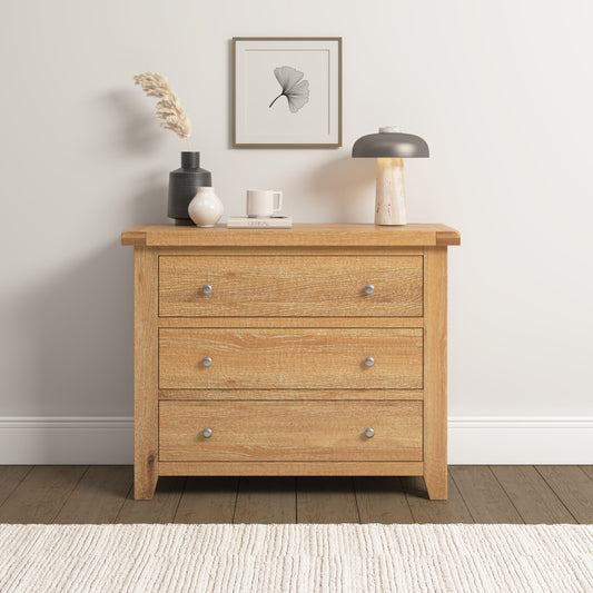 Wooden dresser with three drawers in a room setting with decor items on top.