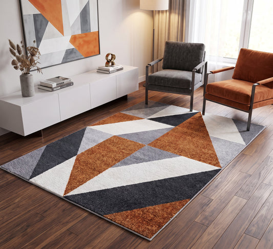 Aspire Rug - 106, orange, grey and white triangle-pattern rug beside dark and orange armchairs on a wooden floor