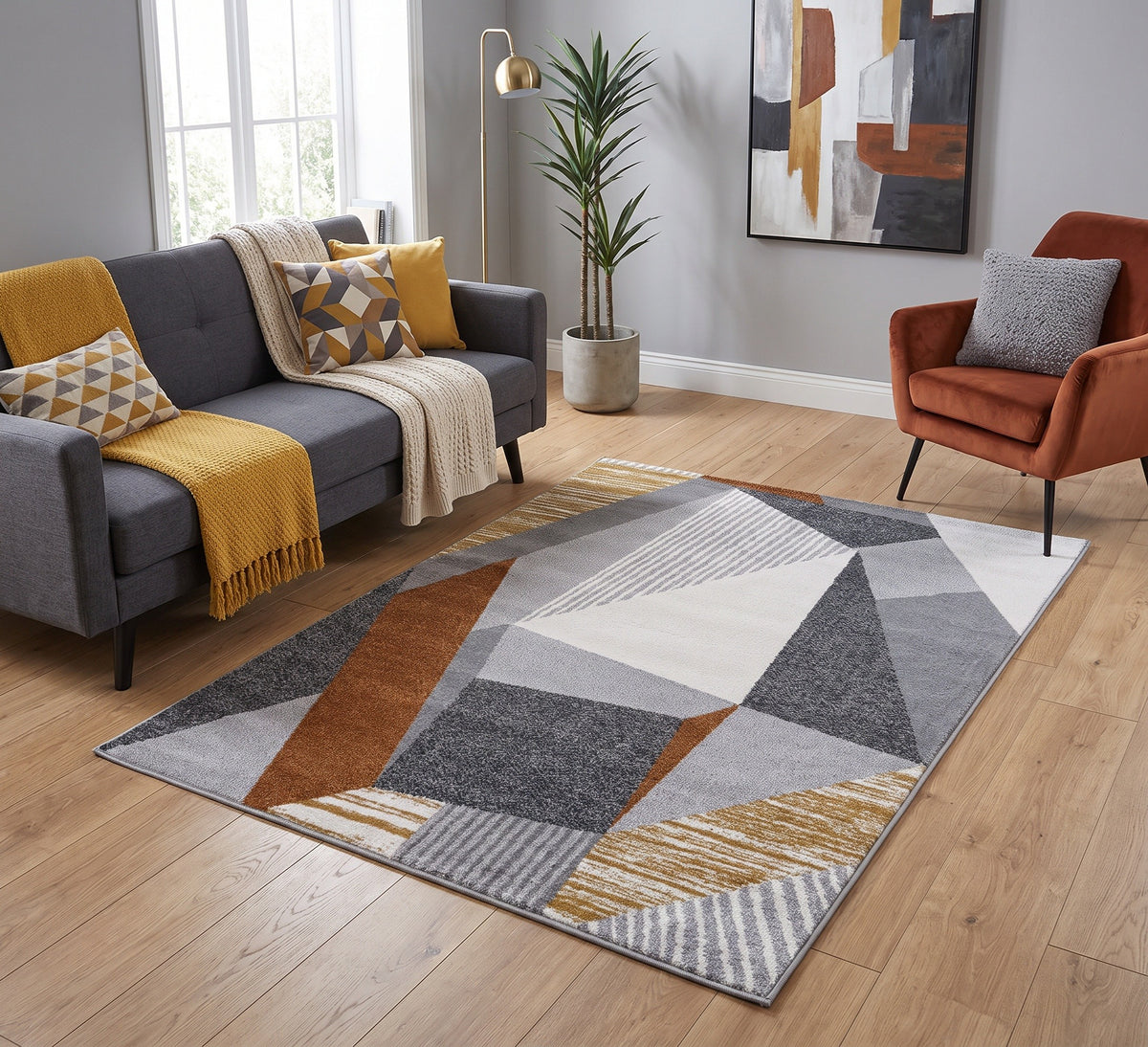 Aspire Rug - 108, grey, rust and mustard geometric rug beside a grey sofa and rust armchair on a wooden floor
