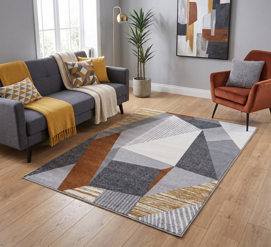 Aspire Rug - 108, grey, rust and mustard geometric rug beside a grey sofa and rust armchair on a wooden floor