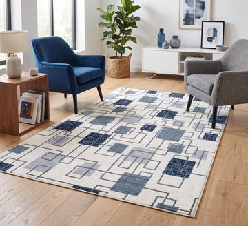 Aspire Rug - Blue, blue square-pattern rug between navy and grey armchairs on a wooden floor
