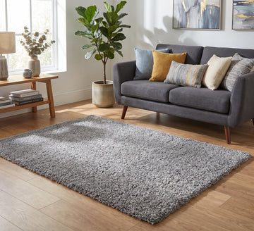 Empire Rug Silver, silver shaggy rug beside a grey sofa