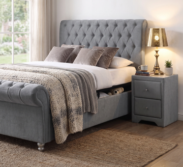 Kilkenny grey side gas-lift bed styled with layered bedding beside a grey bedside locker