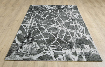 Alisa dark grey and black abstract rug laid flat on a wooden floor